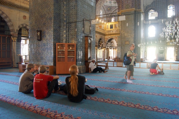 People sitting on the carpet inside the New Mosque in Istanbul