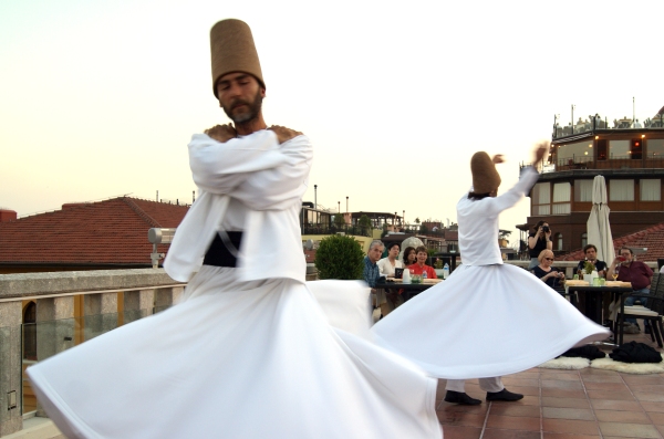 Two dervishes whirling, one with arms outstretched, the other with arms still folded